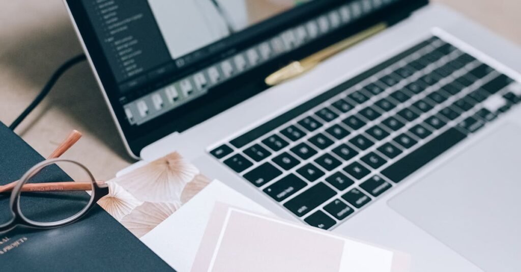 A workspace with a laptop displaying editing software, memory cards, and Pantone color guide.